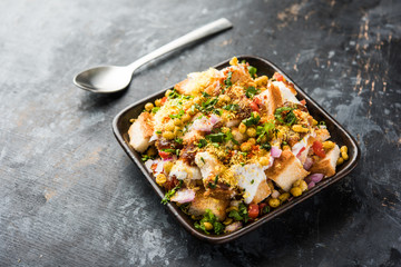 Bread chaat/chat is a yummy starter/appetizer from India, served in a bowl garnished with tomato, sev and coriander and masala. selective focus