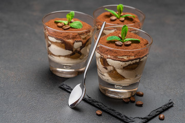 Classic tiramisu dessert in a glass on stone serving board on dark concrete background