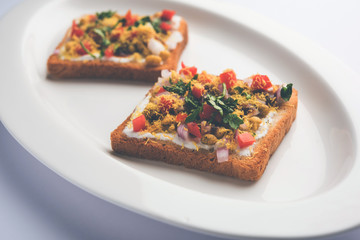 Bread ppadi chaat/chat is a yummy starter/appetizer from India, served in a plate garnished with tomato, sev and coriander and masala. selective focus