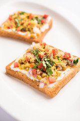 Bread ppadi chaat/chat is a yummy starter/appetizer from India, served in a plate garnished with tomato, sev and coriander and masala. selective focus