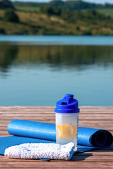 rolled sports mata, towel, and lemon drink on the background of beautiful nature.Healthy lifestyle concept.