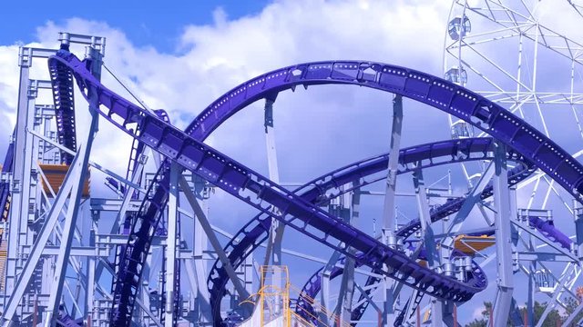 Roller coaster ride in the amusement Park on blue sky background and spinning Ferris wheel at Sunny day.