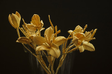 Bouquet of flowers made of straw on a dark background. Close-up