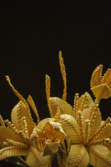 Bouquet of flowers made of straw on a dark background. Close-up