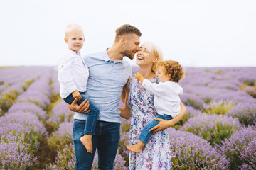 Beautiful portrait of a young family with two baby boys in lavender field. Family love and value...
