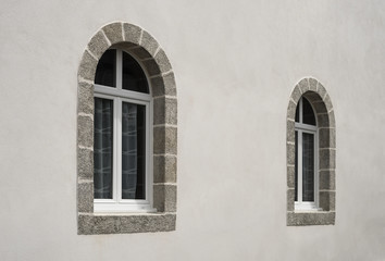 Fototapeta na wymiar Zwei moderne Bogenfenster aus PVC in weißer Fassade perspektivisch - Two modern PVC arched windows in white facade perspective