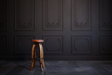 high bar stool against a dark gray wall.