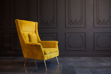 Stylish bright yellow chair against a dark gray wall