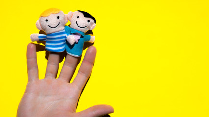 Puppet theater. Hand wearing finger gays family members puppets:  two men partners. lgbt concept.