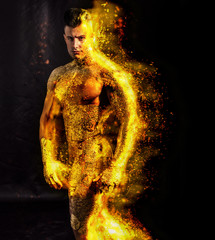 Muscular naked man covered in gold, with fire or flame on his skin, looking down sensually on light...