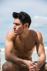 Young fit athletic man at beach in summer day showing muscular torso