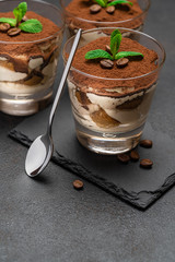 Classic tiramisu dessert in a glass on stone serving board on dark concrete background