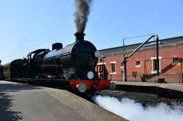 Obraz premium A black steam engine at a station.