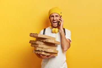 Irritated pizza man calls customer for taking address, holds pile of italian pizza in cardboard...