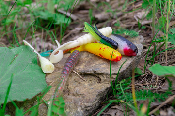 fishing accessories. Baubles and lures lying on a stone with a forest background
