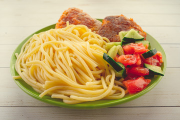 traditional dish consisting of spaghetti with chicken cutlets and vegetable salad.