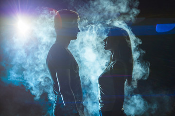 The couple standing in the smoke on a bright light background