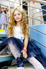 Smiling teen girl with long curly hair sitting on the stairs in the store