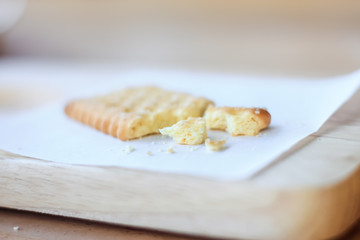 Dry cracker cookies crumb with white paper on wooden plate.