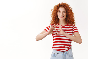 Attractive cheerful glad redhead curly-haired female volunteer trying safe animals wildlife spread love care show heart sign chest smiling broadly feel optimistic express sympathy affection