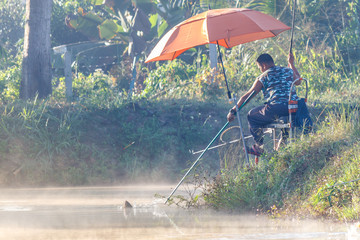 Obraz na płótnie Canvas FANG,CHIANG MAI/THAILAND - DECEMBER 22,2018: Fishermen catch fish at the lake in the morning with beautiful sky