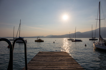 Obraz na płótnie Canvas Boats docked in the Garda Lake at sunset, in the Torri Del Benaco town port; almost sunset, beautiful light