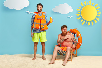 Full length shot of happy male lifeguard advertises sun screen or protection lotion, wears...
