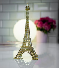 Eiffel tower on a table with a lantern and a flower