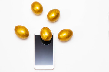 Golden eggs fly out of the smartphone. Concept of wealth