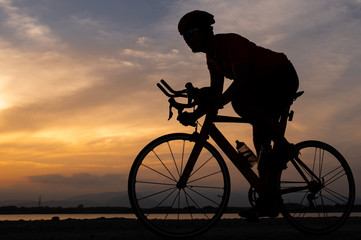 Fototapeta na wymiar Silhouette a road bike cyclist man cycling in the morning.
