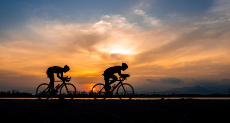 Silhouette two road bike cyclist man cycling in the morning. - obrazy, fototapety, plakaty