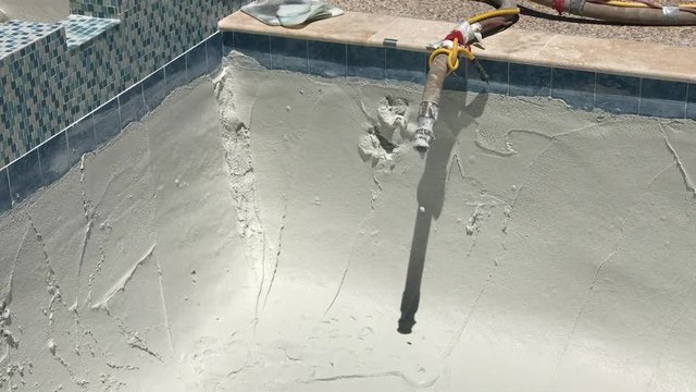 Pool resurface job with hose dripping wet quartz plaster mix pumping and dripping