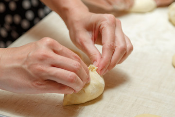 Cooking cherry pies in the home kitchen. Women's hands in the process of cooking cakes with cherries.