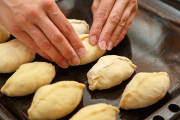Cooking cherry pies in the home kitchen. Women's hands in the process of cooking cakes with cherries.