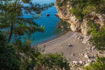 Sea bay with rocky cliff covered with pine trees. Top aerial view of Turkish sandy beach and no people. Horizontal color photography. Turkey.
