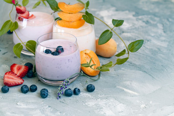 strawberry, blueberry, apricot smoothie on light background decorated with leaves. with fresh berries milkshake. well being weight loos concept. healthy Breakfast. fruit smoothie with ingredients.