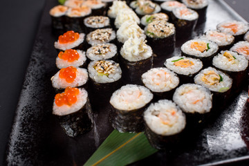 Japanese sushi rolls set served on black plate on dark background