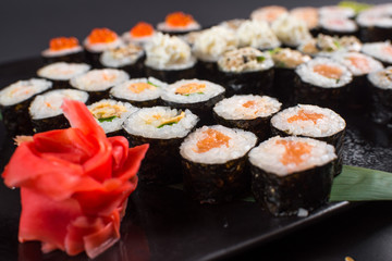 Japanese sushi rolls set served on black plate on dark background