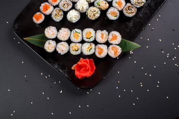 Japanese sushi rolls set served on black plate on dark background