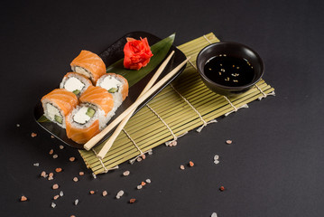 Close up sushi rolls in a black plate on dark background