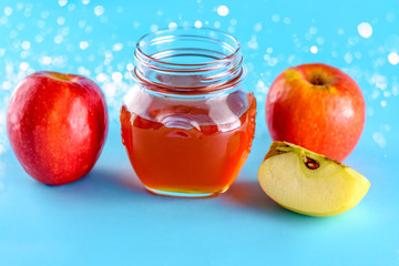 Rosh hashanah jewish holiday concept. Apples and honey jar for jewish new year holiday over blue background. Healthy food. Bokeh lights.