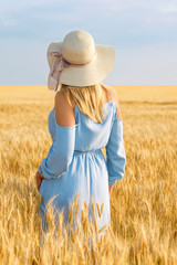 Young woman in yellow wheat field, summer mood at vacation, blue sky. Happiness