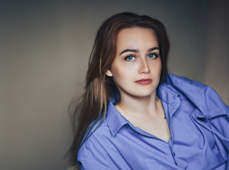 Sexy young beautiful woman with blue big eyes lond hair lying on bed at home in blue shirt