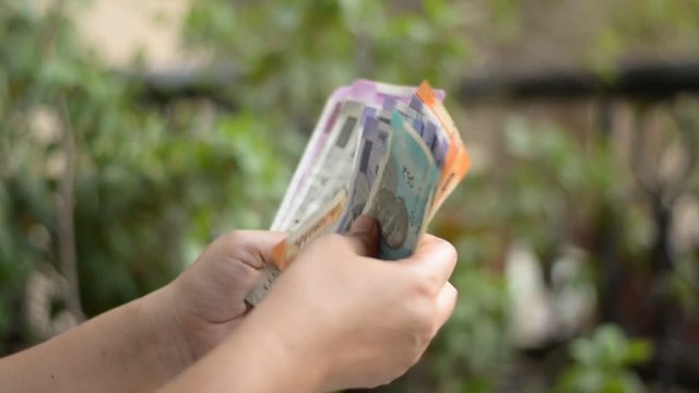 Hands counting new different colorful Indian Rupees Currency notes against a green bokeh background