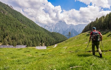 Fototapeta na wymiar Hiker walk on trail and admiring the panorama. Italy Alps.