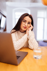 Young woman in kitchen using laptop. Happy female looking at laptop while standing in kitchen in morning.