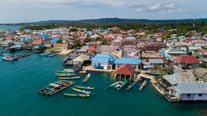 Fototapeta na wymiar Beautiful aerial views of the village near the sea against the background of hills and forests along with many wooden boats lined up near the village