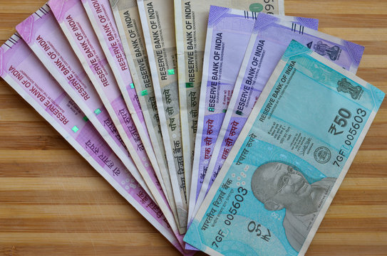 Closeup of brand new colorful Indian currency bank notes of 50,100, 500 and 2000 rupees bundle issued and in circulation after demonetisation against wooden background