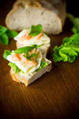 sandwich with cheese, salad leaves and red fish on a wooden