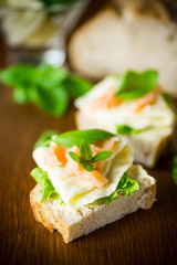 sandwich with cheese, salad leaves and red fish on a wooden